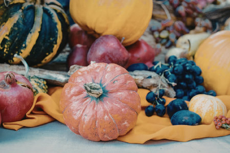 A vibrant still life of pumpkins and various fruits arranged on an orange fabric