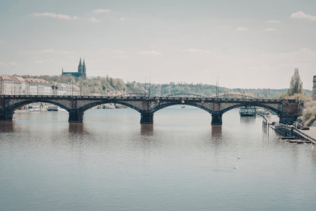 a stone bridge with multiple arches spanning a calm river, with a cityscape in the backgroundの写真素材