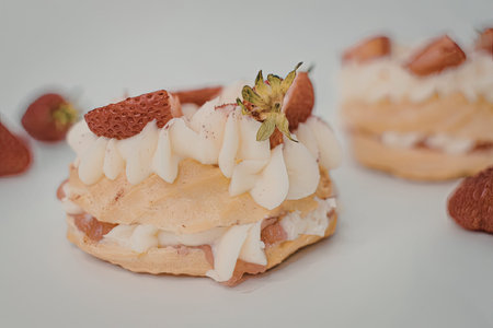 A close-up of a strawberry cream puff pastry dessert with white chocolate shavings and fresh...