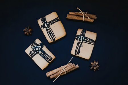 Three wrapped gifts with black ribbons and cinnamon sticks on a dark blue background