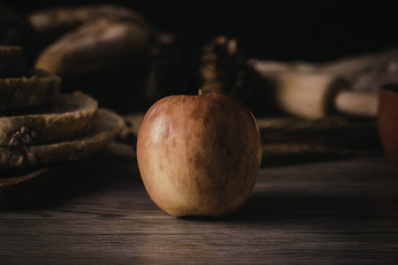 A still life image of a single apple sitting on a wooden table.