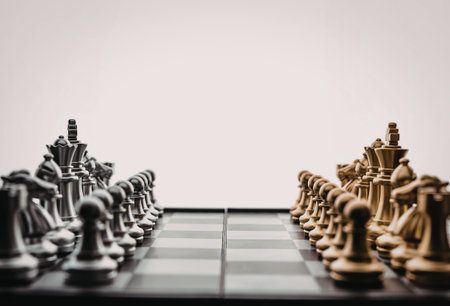 A chess board with black and gold chess pieces arranged for a game on a white background