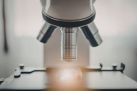 A close-up view of a microscope lens with a bright light shining through it, highlighting the...