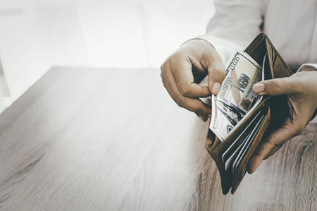 A person holding a brown wallet with cash