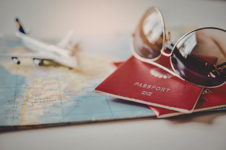 A close-up of travel documents, sunglasses, and a toy airplane on a map.