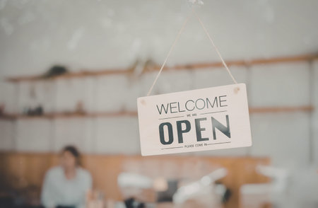 A sign hanging in a store with a blurred background, indicating the store is open for business.
