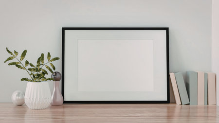 A black picture frame on a wooden table with books and a plant
