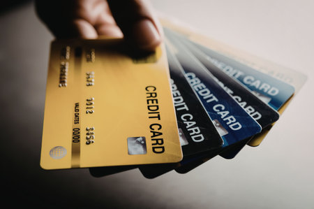 A hand holding a stack of credit cards with different colors and designs.
