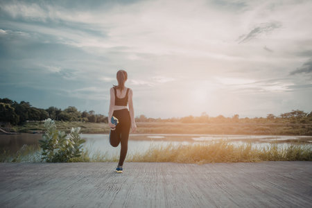 A woman practices outdoors during a serene sunset by a lake, surrounded by nature.