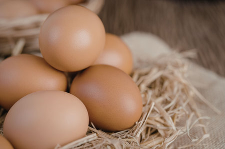A pile of brown eggs on a bed of straw, likely from a farm or a rustic setting.