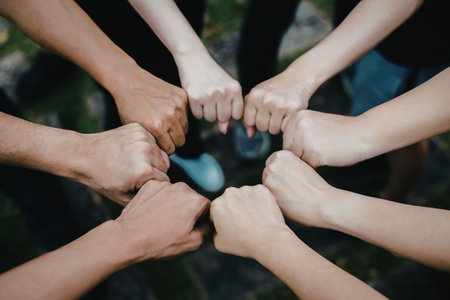 A group of people from different skin tones joining hands together in a circle, symbolizing unity,...