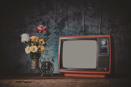 A still life composition featuring a retro red television, a vase with colorful flowers, and a...