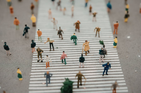 A miniature model of people walking across a crosswalk on a busy street, with many individuals going...