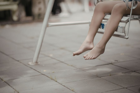 A person's legs hanging from a swing with bare feet