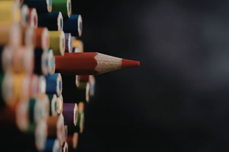 A red colored pencil standing out from a row of other colored pencils.の写真素材