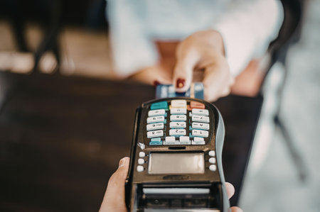 A close-up of a card reader with a person's hand holding it and another person's hand in the...