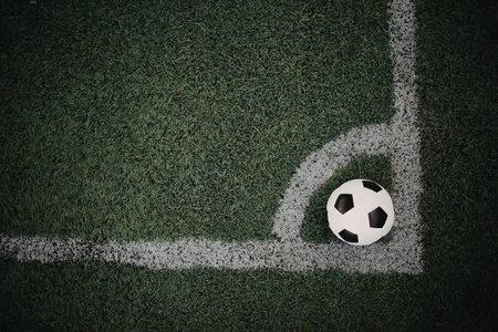 A soccer ball placed on the corner of a green soccer field marked with white lines