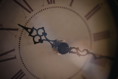 A close-up view of a clock face with a chain and Roman numerals, highlighting the clock's mechanical...