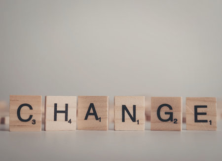 A row of wooden scrabble tiles spelling out the word 'change' on a plain surface