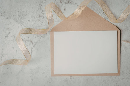 A brown envelope with a white insert and gold ribbon on a marble background