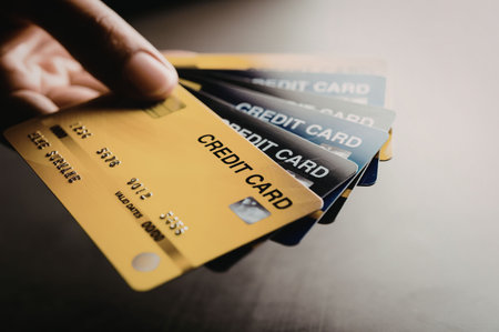 A hand holding a stack of credit cards with different colors and designs