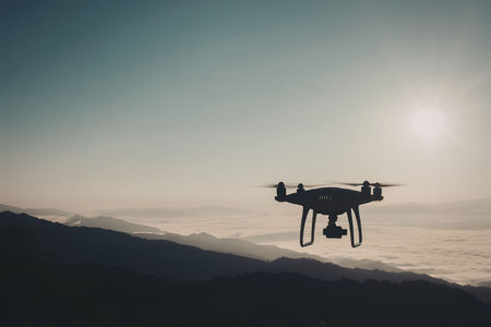 A drone flies over a mountain range at sunset, with the sun shining brightly in the sky.