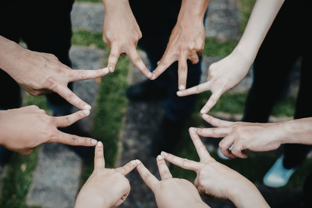 A group of people standing in a circle, forming a heart shape with their hands. The image conveys a...
