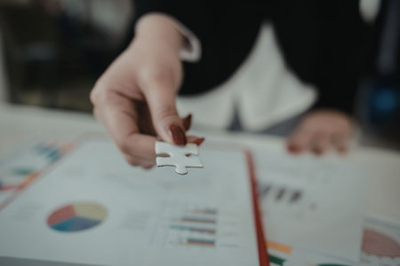 A person analyzing business data with a chart and graph filled document.