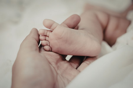 A close-up photo of an adult's hand gently holding a baby's foot.
