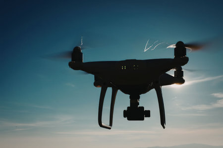 A drone is flying in the sky with the sun shining behind it.