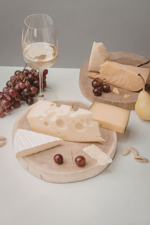 A wine and cheese platter with grapes, cheese, and bread on a white table.