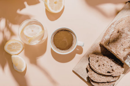 A serene breakfast setup featuring a cup of coffee, a glass of lemonade, sliced bread, and lemons on...