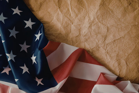 A partially visible American flag with blue, red, and white colors on a brown wrinkled surface.