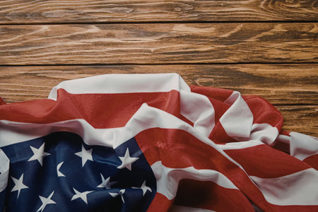 A crumpled American flag placed on a wooden surface, showcasing its red, white, and blue colors with...