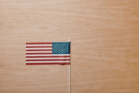 A small American flag on a toothpick against a wooden background