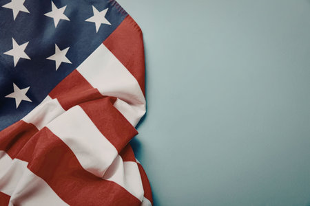 A partially visible American flag on a light blue background, showcasing its iconic red, white, and...