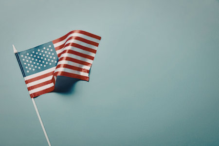 A small American flag on a white pole against a clear blue sky.