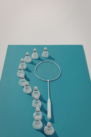 An image of a badminton racket surrounded by shuttlecocks on a blue surface