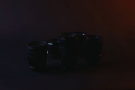 Three black camera lenses are arranged in a row on a dark surface, with a subtle red glow on the...