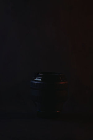 A single camera lens sits in a dark room with subtle lighting effects.