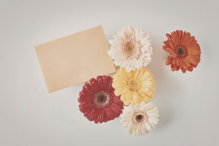 A collection of vibrant flowers next to a blank card on a white background