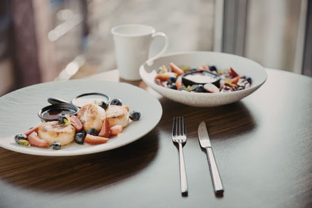A table setting with two plates of food, a bowl of salad, and a cup of coffee, showcasing a healthy...