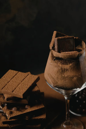 A chocolate dessert in a wine glass with chocolate bars on the side