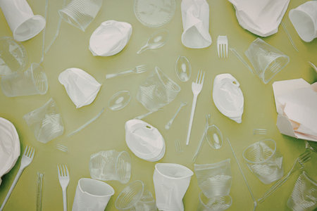 An assortment of disposable plastic tableware and utensils on a green background
