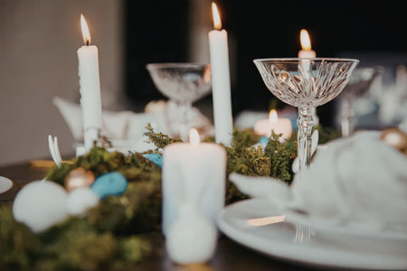 A beautifully set table with white candles, greenery, and decorative glasses, perfect for a formal...