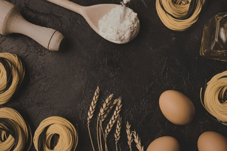A dark surface with fresh pasta, eggs, flour, and wheat.