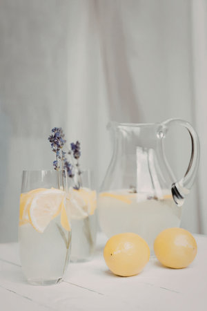 A refreshing glass of lemonade with lavender and lemons on a white table