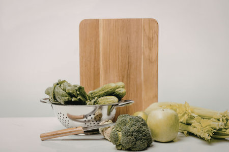 A still life of fresh vegetables on a kitchen counter with a wooden cutting board