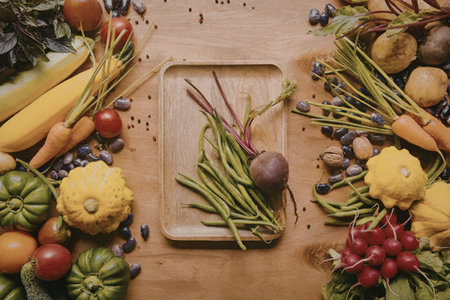 A variety of colorful vegetables arranged on a wooden table, including leafy greens, root...