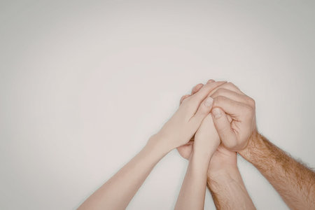An image of two hands clasped together, one larger and hairier suggesting an adult, the other...